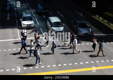 Pedestrians are crossing the road under the hot weather in Singapore, Southeast Asia. Stock Photo