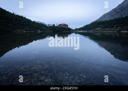 Mountain lodge sitting and reflecting itself on a bank of lake during dusk, Europe, Slovakia Stock Photo