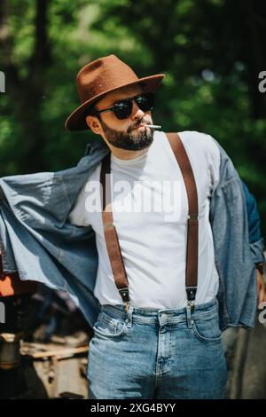 Stylish man wearing suspenders and fedora in vintage outdoor setting Stock Photo