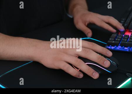 Gamer using modern wired computer mouse at black table, closeup Stock Photo