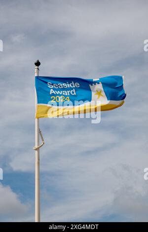 A seaside award flag, flying high, at Fleetwood Ferry Beach, Fleetwood, Lancashire, United Kingdom, Europe on Saturday, 6th, July, 2024 Stock Photo