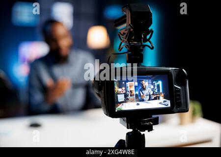 Focus on professional video production gear used for capturing footage of internet star in blurry background filming tech reviews for niche audience, showcasing wireless mechanical keyboard Stock Photo