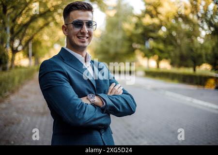 A man dressed in a suit and wearing sunglasses stands on a busy city street. He appears confident and focused. Stock Photo