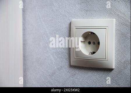 White socket alone on the wall inside the house, close-up Stock Photo