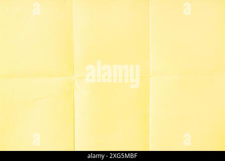 Light Yellow crumpled unfolded paper sheet texture background. Paper folded in six. Full frame Stock Photo