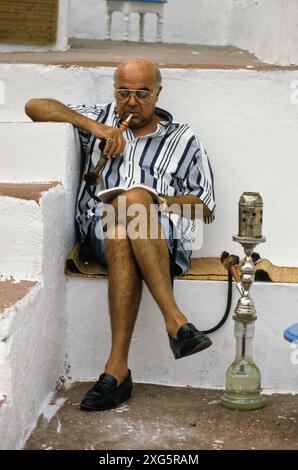 Tunisia, Sidi Bou Said.  Man Smoking a Sheesha, Cafe Sidi Sha'ban. Stock Photo