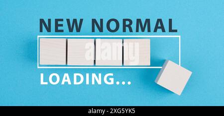 The words new normal are standing on wooden cubes, loading bar, blue colored background Stock Photo