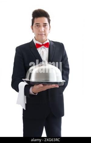 Handsome yong waiter in tuxedo and gloves holding empty tray and napkin on white isolated Stock Photo