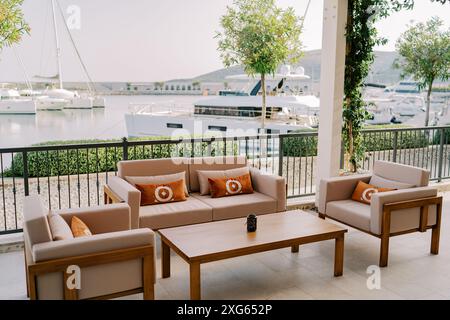 Sofa and armchairs with pillows stand near a wooden table on a terrace on the promenade Stock Photo