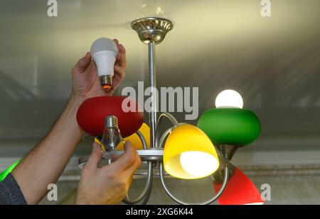 replacing an incandescent light bulb with an energy efficient LED lamp Stock Photo