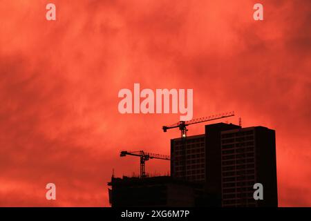 Silhouette of constructing buildings against amazing red sky Stock Photo