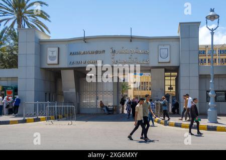 People walk outside the main gate of Alexandria University Faculty of Commerce on a sunny day in Alexandria, Egypt Stock Photo