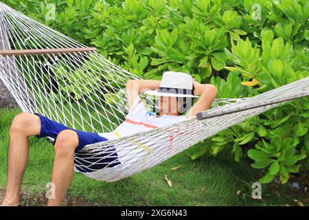 People taking a nap on the hammock in tropical garden Stock Photo