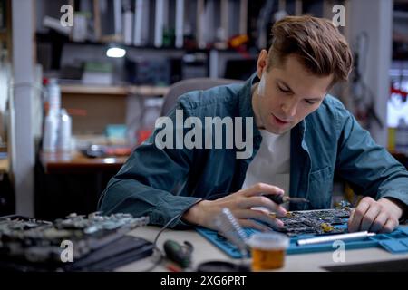 young technician or Engineer installing CPU microprocessor to motherboard socket on workplace in the office. Concept of repairing, upgrade, service, e Stock Photo