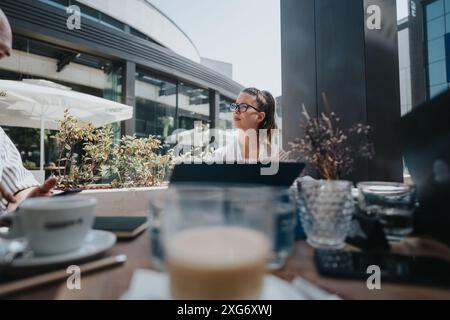 Startup team in a business meeting discussing, brainstorming, and strategizing over coffee in an outdoor cafe Stock Photo