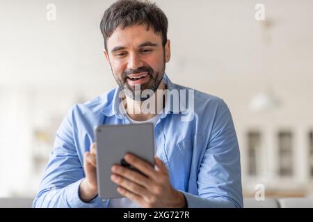 Happy Man Using Tablet in Casual Setting Stock Photo