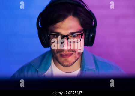 Young Man Wearing Headphones and Glasses Playing Game Stock Photo