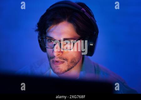 Young Man Wearing Glasses and Headphones Concentrating on Computer Screen Stock Photo