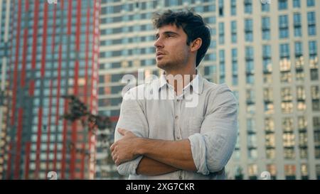 Portrait of handsome young business man 30s millennial confident guy looking at camera crossed hands posing on street successful male model in city Stock Photo