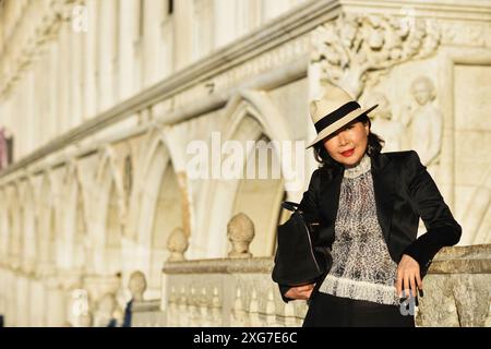 A glamorous well dressed tourist on Ponte della Paglia enjoying the views of Venice on a sunny morning by the Doges Palace Stock Photo