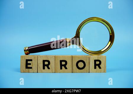 Error with wooden blocks alphabet letters and Magnifying glass on blue background Stock Photo
