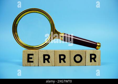 Error with wooden blocks alphabet letters and Magnifying glass on blue background Stock Photo