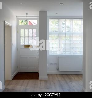 Minimalist, white painted front door and entrance hallway of an Edwardian house converted into flats in north London. Stock Photo