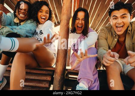 Group of four joyful friends having fun and laughing together outside. Capturing the essence of friendship, happiness, and unity. Stock Photo