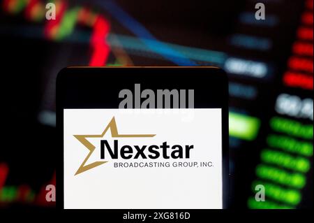 June 23, 2024, China: In this photo illustration, the American media company, Nexstar Media Group (NASDAQ: NXST), logo seen displayed on a smartphone with an economic stock exchange index graph in the background. (Credit Image: © Budrul Chukrut/SOPA Images via ZUMA Press Wire) EDITORIAL USAGE ONLY! Not for Commercial USAGE! Stock Photo