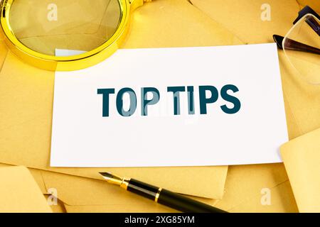 top tips word. text concept symbol TOP TIPS on a white business card lying on postal envelopes Stock Photo