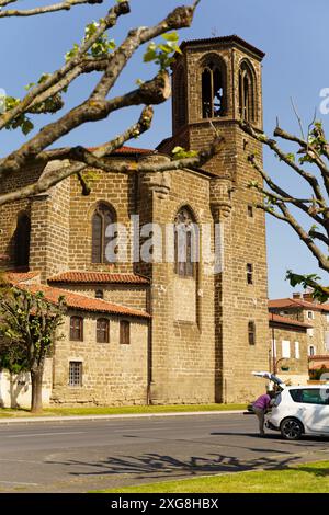 Langeac, France - May 27, 2023: A stone church tower with a bell tower and stained glass windows rises above the streets of Langeac, France, seen thro Stock Photo