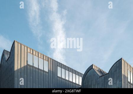 A striking modern architectural building with a sleek design, featuring large windows and a metal facade. Stock Photo