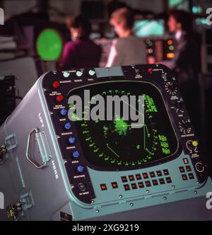 Close-up of vintage air traffic control radar screen showing aircraft blips and vectors, with controllers working in blurred background Stock Photo