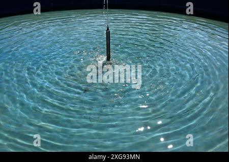 small fountain and radial waves on the water surface Stock Photo