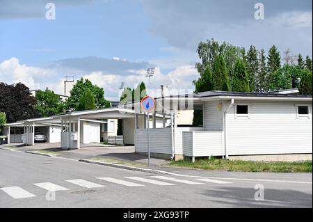 This photo depicts a peaceful suburban neighborhood with modern white houses featuring carports. A crosswalk and a no parking sign are visible on the Stock Photo