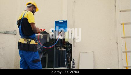 Proficient worker calibrating set of barometer indicators during comissioned condenser analysis. Qualified electrician looking for potential high pressure in hvac system cooling system Stock Photo