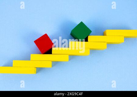 Green and red cubes overcoming ladder levels to achieve their goals Stock Photo