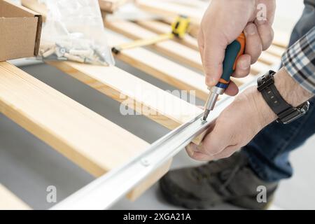 Close up of a hands Assembling a bed frame using a screwdriver. Furniture mounting concept Stock Photo