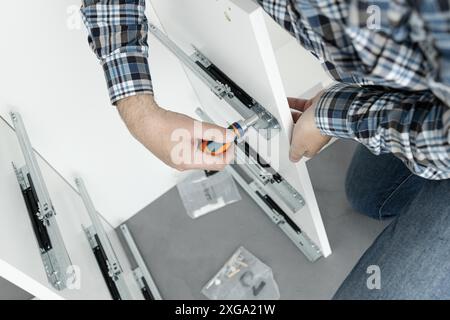 Close up of a Man Assembling a drawer slider Furniture using a screwdriver Stock Photo