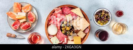 Italian antipasti or Spanish tapas panorama. Gourmet cold meat and cheese platter on a table, shot from the top with wine. A variety of appetizers. Stock Photo