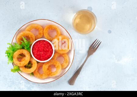 Squid rings. Deep fried calamari rings with ketchup, lettuce, and white wine, top shot with a place for text Stock Photo