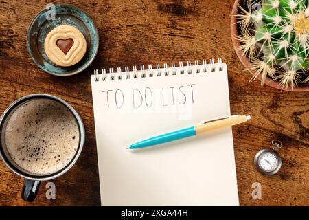 To do list, top shot of a notebook on a wooden desk, with a blue pen and a coffee mug, a flat lay. The concept of planning, time management Stock Photo