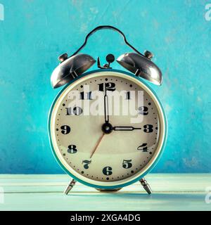 A retro alarm clock on a vibrant blue background, the concept of time, square image Stock Photo