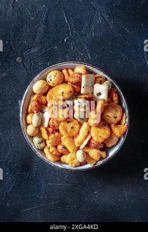 Japanese rice crackers in a bowl on a black slate background, shot from above with a place for text Stock Photo