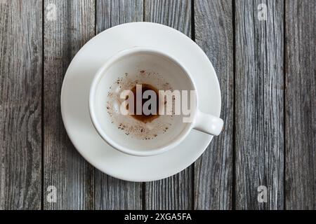 Empty cup with coffee leftovers on wooden table, closeup Stock Photo