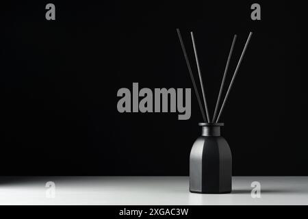Black Reed Diffuser Bottle On White Surface Against Black Background Stock Photo