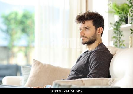 Pensive serious man looking away sitting on a couch at home Stock Photo