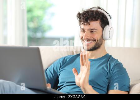 Happy man having video call on laptop sitting on a couch at home Stock Photo