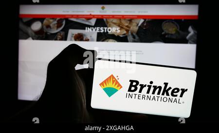 Person holding smartphone with logo of US hospitality company Brinker International Inc. in front of website. Focus on phone display. Stock Photo