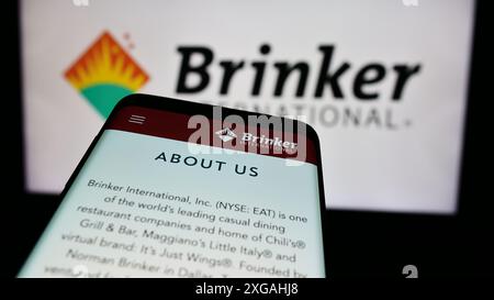 Smartphone with website of US hospitality company Brinker International Inc. in front of business logo. Focus on top-left of phone display. Stock Photo